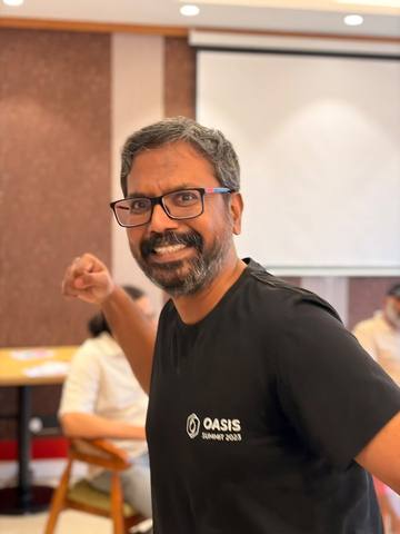 Shemeer grinning, fist raised, in a black OASIS Summit T-shirt